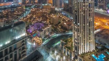 Gece vakti otelleri olan büyük, fütürist bir şehrin havadan panoramik görüntüsü. Dubai, Birleşik Arap Emirlikleri 'nin gökdelenleri ve geleneksel evleri olan iş sahası ve şehir merkezi..