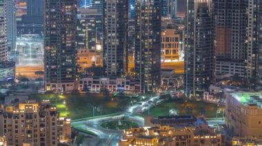 Aerial view of traffic on circle intersection a big futuristic city night timelapse. Business bay and Downtown district with many skyscrapers and traditional houses, Dubai, United Arab Emirates