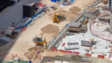Kazıcılar ve buldozerler yeni gökdelen hava zaman çizelgesinin şantiyesinde çalışıyorlar. Arazi temizliği, not verme, havuz kazma, siper kazma ve temel kazma. Sürüngen traktörü ve yer değiştirme ekipmanları