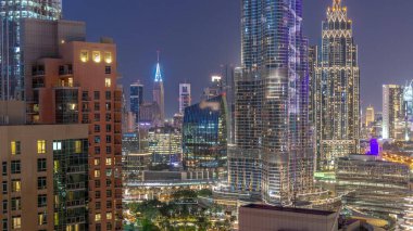 Dubai Uluslararası Finans Merkezi bölge gökdelenlerinin şehir merkezinden gece gündüz geçiş zamanının hava görüntüsü. Camdan ofis kuleleri ve modern binaları olan oteller.