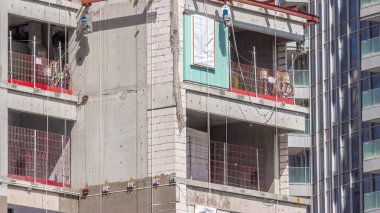 İnşaat askıya alınmış beşik inşaat halindeki bir evin duvarında asılı duruyor. Pencere kurulum süreci