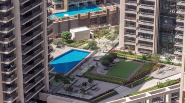 Dubai şehir merkezinde havuzu ve güneşli yatağı olan gökdelenler arasında dinlenme alanı. Gölgeler hızla hareket ederken yukarıdan gökyüzü görüntüsü