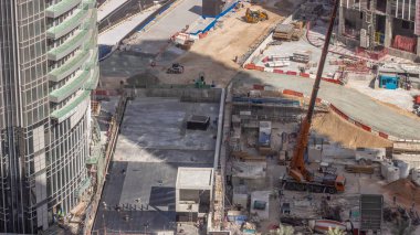 Vinçler ve buldozerler yeni gökdelen hava zaman çizelgesinin şantiyesinde çalışıyorlar. Çatı kaplaması. Arazi temizliği, not verme, havuz kazma, siper kazma ve temel kazma. Sürüngen traktörü ve yer değiştirme ekipmanları