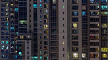 Gece karanlığında parlayan gökdelen dairesinin camları şehrin ışıklarını yansıtıyor. Balkonları olan aydınlık kuleler