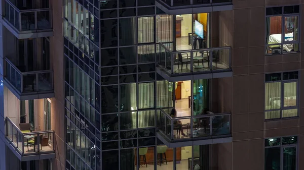 Apartman binasındaki parlayan panoramik pencerelerin gece görüşü. Odalarında ışıklar olan yüksek gökdelenli.