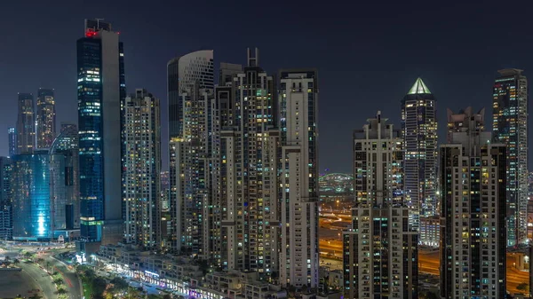 Business Bay hava sahasında modern kuleleri olan Bay Bulvarı. Gece uçuşu, Dubai, BAE. Parlak pencereli gökdelenler