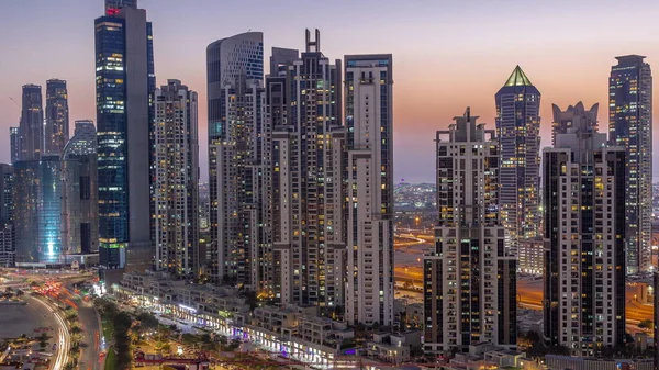 Business Bay hava sahasında modern kuleleri olan Bay Bulvarı 'nda gündüz gece geçiş zamanı, Dubai, BAE. Gün batımından sonra gökdelenler