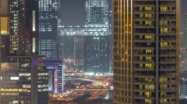 Dubai Uluslararası Finans Merkezi 'ndeki kuleler. Bölgesel hava gece zaman çizelgesi. Modern gökdelenleri olan ofis binaları ve oteller inşaat ve üstgeçit trafiği altında