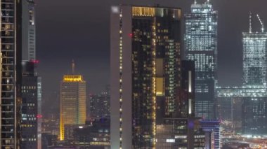 Dubai Uluslararası Finans Merkezi 'ndeki kuleler. Bölgesel hava gece zaman çizelgesi. Modern gökdelenleri yapım aşamasında olan ofis binaları ve oteller