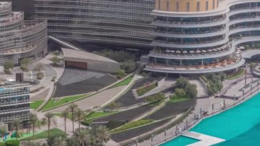 Dubai şehir merkezinde fıskiyelerin yanında alışveriş merkezi ve modern fütüristik mimari hava zaman dilimi ile. Avuç içleriyle yürüme alanına yakın görünüm