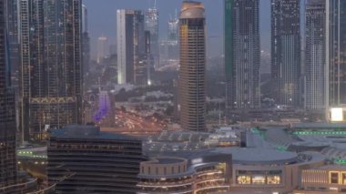 Dubai şehir merkezinde fıskiyelerin yanında ve modern fütüristik mimari hava gününden geceye geçiş zamanı. Finans bölgesindeki gökdelenlere ve alışveriş merkezlerine bak