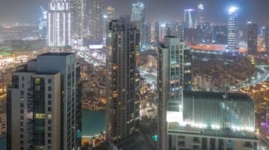 Aerial panoramic view of futuristic city during all night timelapse. Business bay and Downtown district with lights turning off in skyscrapers and traditional houses, Dubai, United Arab Emirates