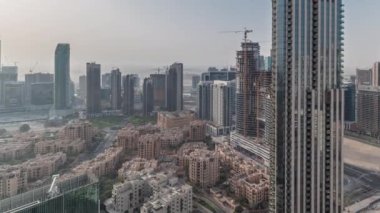 Sabah vaktinde büyük, fütüristik bir şehrin havadan panoramik silueti. Gökdelenleri ve geleneksel evleri olan iş sahası ve şehir merkezi bölgesi, Dubai, Birleşik Arap Emirlikleri
