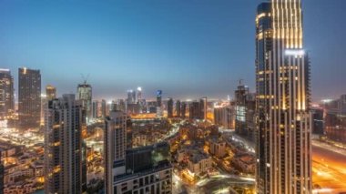 Aerial panoramic view of a big futuristic city night to day transition timelapse. Business bay and Downtown district before sunrise with skyscrapers and traditional houses, Dubai, United Arab Emirates