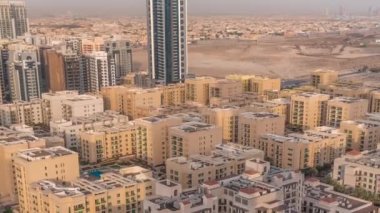 Yeşiller bölgesindeki alçak katlı binalar ve Barsha Heights bölgesindeki gökdelenler. Dubai silueti arkasında villalar olan