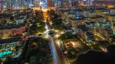 Barsha Heights bölgesindeki gökdelenler ve Greenens bölgesindeki alçak binalar gece panoramik zaman çizelgesi. Sokaklarda trafik varken Dubai silueti