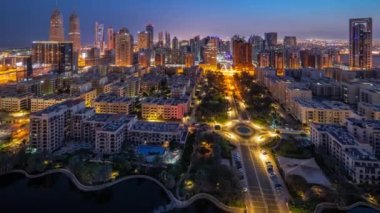 Barsha Heights bölgesindeki gökdelenler ve Greenens bölgesindeki alçak binalar gece gündüz panoramik zaman atlamaları. Palmiyeler ve ağaçlarla Dubai silueti