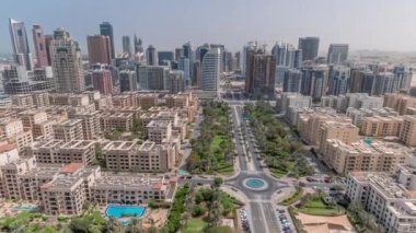 Barsha Heights bölgesindeki gökdelenler ve tüm gün boyunca Greenens bölgesindeki alçak binalar. Dubai 'nin palmiyeler ve ağaçlarla kaplı panoramik silueti. Gölgeler hızlı hareket ediyor