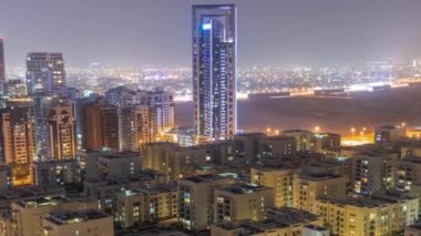 Barsha Heights bölgesinde gökdelenler ve tüm gece boyunca Greenens bölgesinde alçak binalar. Dubai silueti arkaplanda çöl var.