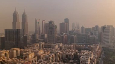 Barsha Heights bölgesindeki gökdelenler ve sabah sisli hava saatleriyle birlikte gün doğumunda Yeşiller bölgesindeki alçak binalar. Palmiyeler ve ağaçlarla Dubai silueti