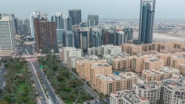 Yeşiller bölgesindeki alçak katlı binalar ve Barsha Heights bölgesindeki gökdelenler panoramik zaman aralığında günden geceye geçiş. Palmiyeler ve ağaçlarla Dubai silueti
