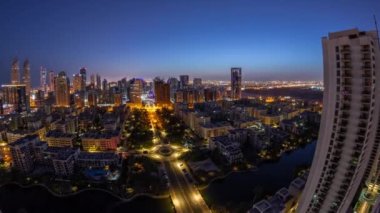 Barsha Heights bölgesindeki gökdelenler ve Greenens bölgesindeki alçak binalar gece gündüz geçiş zamanı panorama. Palmiyeler ve ağaçlarla Dubai silueti
