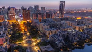 Barsha Heights bölgesindeki gökdelenler ve Greenens bölgesindeki alçak binalar gece gündüz geçiş zamanları. Dubai silueti yol kavşağı yakınında ağaçlarla kaplı.