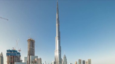 Dubai şehir merkezi gökdelenleri havadan yayılan panoramik zaman çizelgesiyle günbatımında camdan yansıyan güneş. Yukarıdan gelen trafiğin yoğun olduğu yeni kulelerin ve yolların inşa edildiği yer
