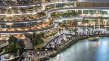 Alışveriş merkezinin balkonunda Dubai şehir merkezindeki çeşmenin yanında reataurantlar, Birleşik Arap Emirlikleri. Aydınlatılmış sahil yürüyüşü alanı