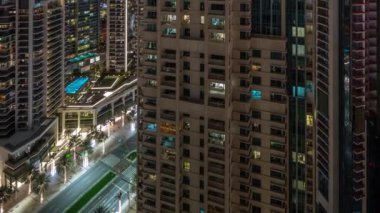 Dubai şehir merkezinin aydınlatılmış mimarisi ile hava şehri gece zaman çizelgesi. Parlak pencereli birçok uzun gökdelen ve kuleler. Bulvar yolunda trafik vardı.
