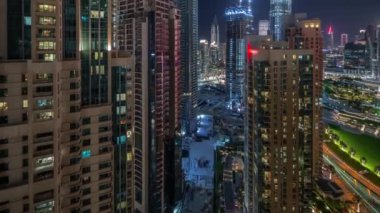 Dubai şehir merkezinin aydınlatılmış mimarisi ile hava şehri gece zaman çizelgesi. Parlak pencereli birçok uzun gökdelen ve kuleler. Yeni inşaat alanı.