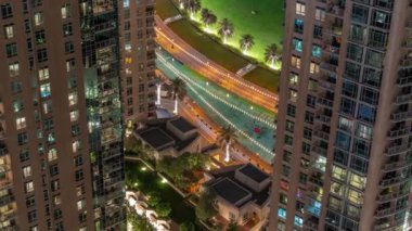 Fıskiyelerin yanındaki yeşil çimenli park. Dubai şehir merkezindeki yapay gölün iki kulesi arasındaki görüntüyü al. Palmiyeler ve ağaçlarla yukarıdan görünüm