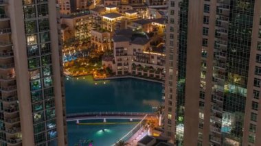 Gökdelenler arasında gece görüşü etrafında yürüyen Dubai çeşmeleri. Alışveriş merkezinin yakınındaki eski kasabada geleneksel evleri olan mimari