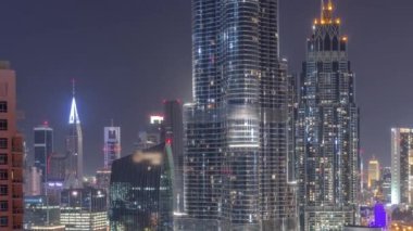 Şehir merkezinden tüm gece boyunca Dubai Uluslararası Finans Merkezi 'nin gökdelenlerinin hava görüntüsü. Aydınlatma kapalı camdan ofis kuleleri