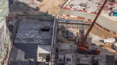 Vinçler ve buldozerler yeni gökdelen hava zaman çizelgesinin şantiyesinde çalışıyorlar. Çatı kaplaması. Arazi temizliği, not verme, havuz kazma, siper kazma ve temel kazma. Sürüngen çekici