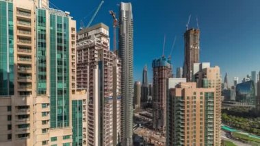 Şehir merkezindeki modern Dubai mimarisi ile havadan çekilmiş zaman çizelgesi. Cam yüzeyi olan birçok yüksek gökdelen ve kule. Yeni inşaat alanı. Gölgeler hızlı hareket ediyor