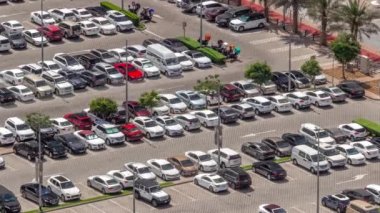 İş merkezinin otopark arabalarının, alışveriş merkezinin, arabaların ve boş park yerlerinin hava manzarası. Gün boyunca gölgeler hızla hareket ediyor.
