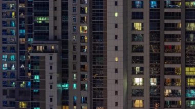 Gece karanlığında parlayan gökdelen dairesinin camları şehrin ışıklarını yansıtıyor. Balkonları olan aydınlık kuleler