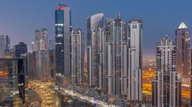 Business Bay hava sahasında modern kuleleri olan Bay Bulvarı. Gece gündüz geçiş zamanı, Dubai, BAE. Parlak pencereli gökdelenler