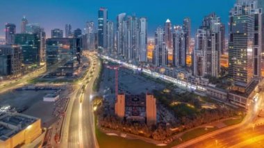 Business Bay hava sahasında modern kuleleri olan Bay Bulvarı gece gündüz panoramik geçiş zamanı, Dubai, BAE. Büyük otoparkın yakınındaki yolda trafiği olan gökdelenler.