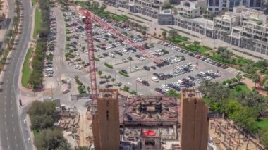 İş merkezinin park alanındaki arabaların hava manzarası, inşaat alanının yakınındaki tüm gün boyunca arabalı alışveriş merkezleri ve boş noktalar. Gölgeler gün batımına kadar hızla ilerliyor