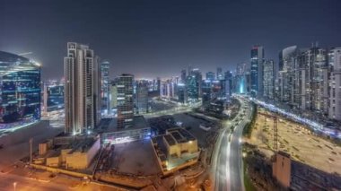 Business Bay havacılık panoramik gece zaman çizelgesinde aydınlatmalı modern kuleleri olan Bay Avenue, Dubai, BAE. İnşaat alanı olan gökdelenler