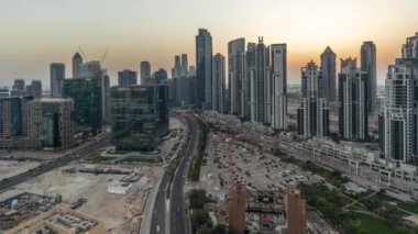 Bay Bulvarı 'nın Panorama' sı, Business Bay hava sahasında modern kuleler, gündüz, gece geçiş zamanı, Dubai, BAE. Büyük otoparkın yakınındaki yolda trafiği olan gökdelenler.