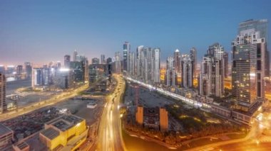 Business Bay hava sahasında modern kuleleri olan Bay Bulvarı 'nda gece gündüz geçiş zamanı panorama, Dubai, BAE. Büyük otoparkın yakınındaki yolda trafiği olan gökdelenler.