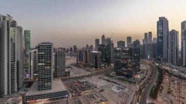Modern kuleleri olan Business Bay 'de konut geliştirme panoramik havadan geceye geçiş zamanı, Dubai, BAE. Gün batımından sonra büyük otoparkın yakınındaki yolda trafiği olan gökdelenler.