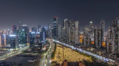 Bay Bulvarı 'nda aydınlatmalı modern kuleler Business Bay havacılık panoramasında yerleşim alanları var. Bütün gece boyunca Moon, Dubai, BAE ile birlikte. Büyük otoparkın yanındaki yolda trafiği olan gökdelenler.