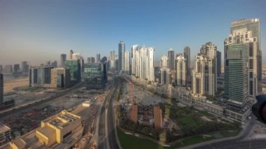 Gündoğumundan batımına, Dubai, BAE 'ye kadar bütün gün boyunca Business Bay' de modern kuleleri olan panorama. Büyük otoparkı olan gökdelenler.