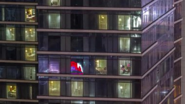 Gece karanlığa bürünmüş gökdelen perdeleri olan apartman pencereleri şehrin ışıklarını yansıtan zaman ayarlı yansıtmalı. Aydınlatılmış kuleler