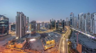 Business Bay hava sahasında modern kuleleri olan Bay Bulvarı gece gündüz panoramik geçiş zamanı, Dubai, BAE. Yol ve inşaat alanında trafiği olan gökdelenler