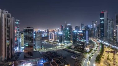 Su kanalı aydınlatmalı modern kuleler Business Bay 'de konut geliştirme panoramik tüm gece boyunca zaman ayarlı, Dubai, BAE. Yolunda trafik olan ve ışıkları kapanan gökdelenler.